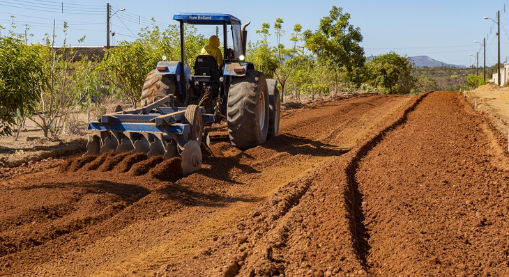 Trator realiza tratamento de solo para terraplanagem de rua no Morada do Sol