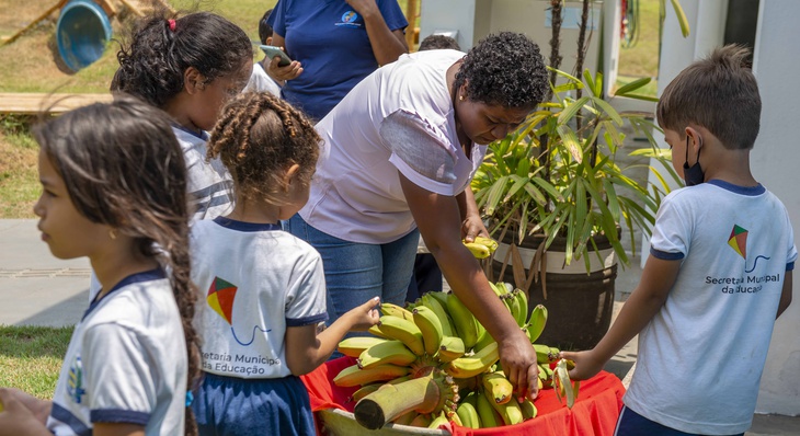 Diretora Evercina Barbosa recebendo os cachos de bananas junto com os alunos do Cmei