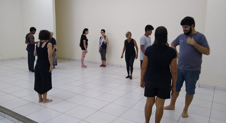 Idosos e alunos praticam exercícios durante oficina de teatro