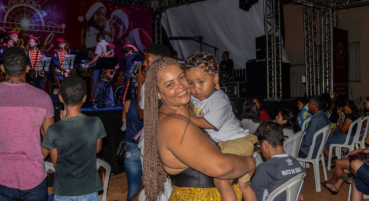 Diana e o pequeno Luiz Otávio assistem a Nickole no palco com sua banda do Cemil