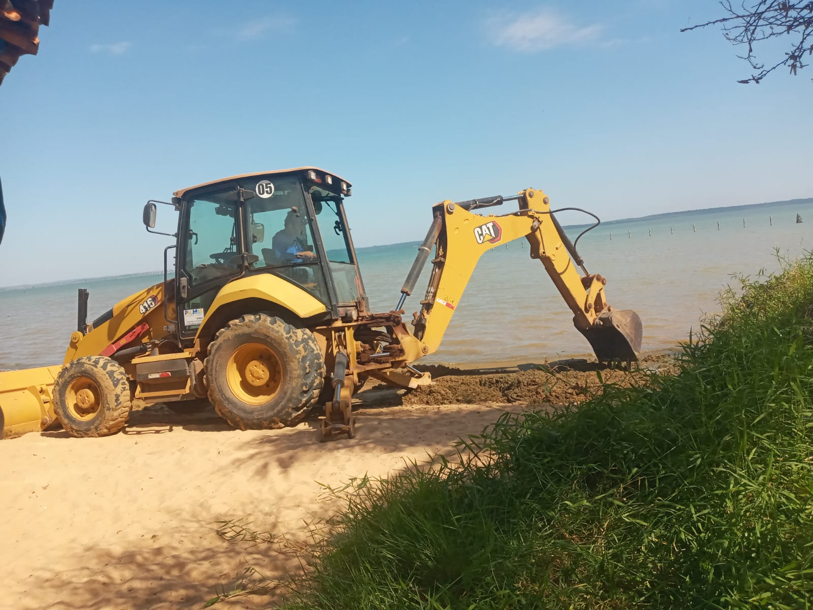 Trator realizando limpeza na faixa de areia da Praia das Arnos