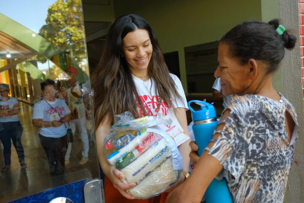 Moradora da região norte recebendo cesta básica durante ação deste sábado, 7- Foto: Gabriel Trevisan- Love Together Brasil